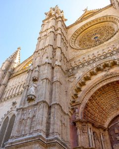Colorful sailing yachts moored at sunset on the calm sea, with vibrant flags flying from their masts, creating a lively and picturesque maritime scene.
